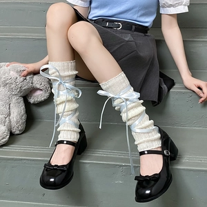 Beige knit leg warmers with blue satin ribbons paired with black Mary Jane shoes