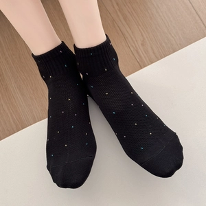 Gros plan de chaussettes résille noires à pois colorés avec bords-côtes élastiques