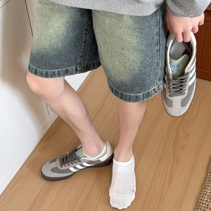 Detail of retro sneakers with grey suede and white stripes on vintage denim street style