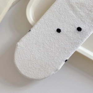 Close-up of white cotton socks with black polka dot patterns and knitted texture