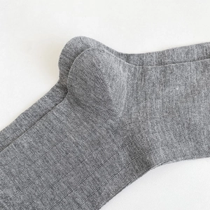 Détail de chaussettes hautes grises montrant le talon renforcé et la texture côtelée