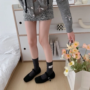 Détail de chaussettes en maille gris foncé à pois rouges avec étiquette et chaussures noires