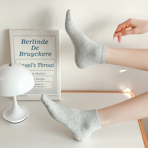 Détail de chaussettes en tricot gris clair à pois colorés et revers côtelés sur un modèle