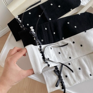 Detail of polka dot mid-calf socks with elegant ribbon bows and lace trim decoration