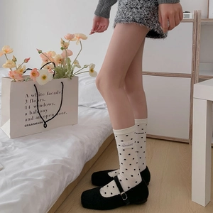 Détail de chaussettes blanches à pois avec étiquette en tissu et chaussures Mary Jane