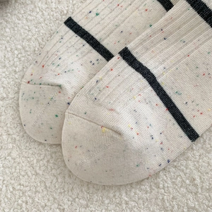 Macro detail of cream ribbed knit socks with black stripes and colorful confetti yarn texture