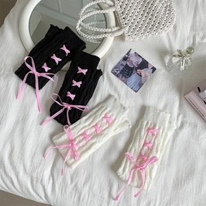 Detail of cable knit leg warmers with pink lace-up ribbons and sweet bow accents