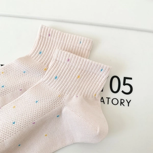 Gros plan de chaussettes en résille rose à pois colorés et bords-côtes pour la respirabilité