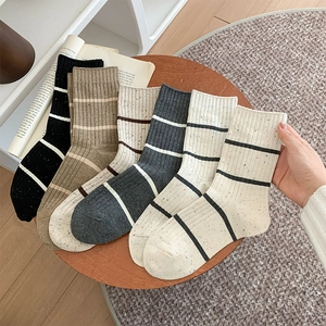 Detail of five-pair set of striped cotton socks in assorted neutral colors on wooden surface