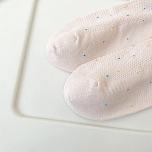Détail de chaussettes rose clair avec pois colorés et texture en maille respirante