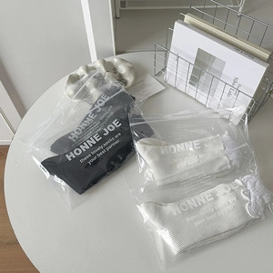 Detailed view of three pairs of mesh socks in branded frosted zipper bags on a white table