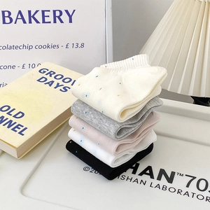 Gros plan de cinq paires de chaussettes en coton à pois colorés sur un plateau blanc