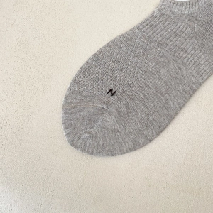 Macro detail of breathable knit cotton sock with black embroidered letter N