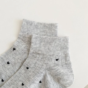 Detailed view of grey cotton socks featuring black heart patterns and ribbed cuffs