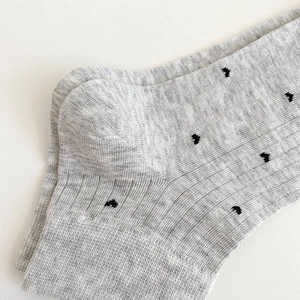 Macro shot of grey knitted cotton socks with tiny black pattern and ribbed texture details