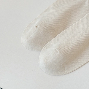 Close-up of beige knitted cotton socks showing vertical ribbed texture and toe seam