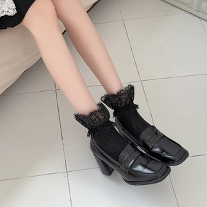 Détail de chaussettes à bordure en dentelle noire portées avec des mocassins à talons hauts