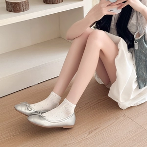 Gros plan sur des chaussettes résille blanches à pois portées avec des ballerines argentées