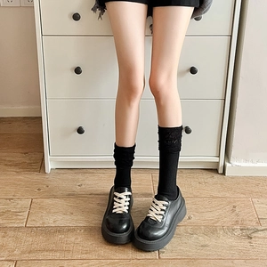Close-up of black lace mesh socks paired with matte platform derby shoes on a model