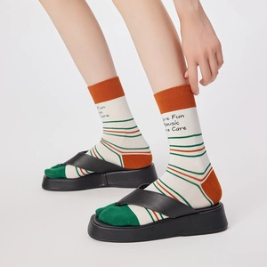 Detail of striped split-toe socks in beige and orange paired with black flip-flop sandals