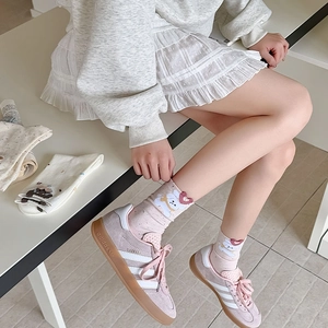 Detail of pink cotton socks with bear embroidery paired with pastel sneakers
