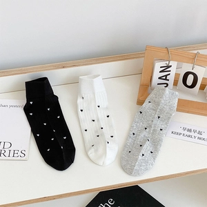 Detail of three pairs of cotton socks in black, white, and grey with heart patterns
