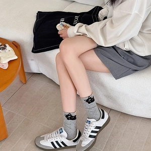 Detail view of gray crew socks with black cat pattern and ribbed cuffs on model