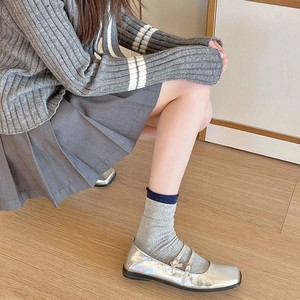 Detail view of silver Mary Jane shoes with double buckles paired with retro rib knit socks