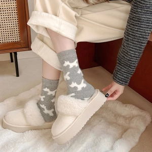 Detail showing plush beige platform mule slippers paired with grey dog pattern wool socks