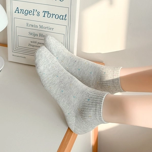 Chaussettes en tricot gris clair à pois colorés dans un cadre intérieur doux