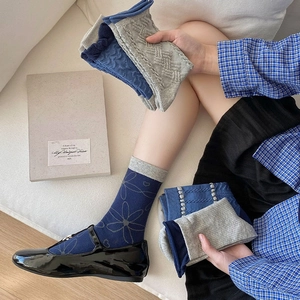 Detailed knit patterns of blue floral relief and wavy lace trim on vintage crew socks