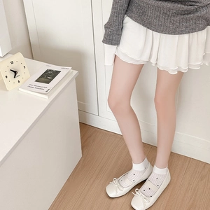 Detailed view of white heart pattern socks paired with Mary Jane shoes and a white skirt