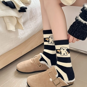 Détail de chaussettes thermiques rayées avec motif chien et chaussons en peluche d'hiver