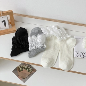 Détail de trois paires de chaussettes à bordure en dentelle en noir, gris et blanc crème