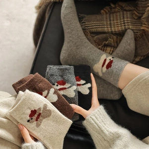Macro detail of thick knitted wool socks featuring cute bear patterns in four warm colors