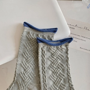 Detail of grey jacquard knitted socks featuring vibrant blue rolled cuffs and textured patterns