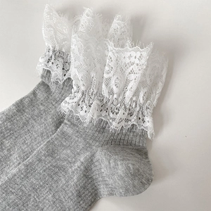 Détail de chaussettes grises en tricot avec bordure en dentelle blanche et maille côtelée