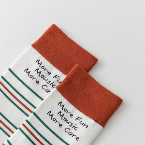 Macro detail of striped knit tabi socks with orange ribbed cuffs and text embroidery