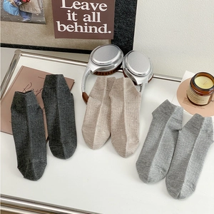 Detailed knit texture of low-cut mesh socks in charcoal, beige, and light gray tones