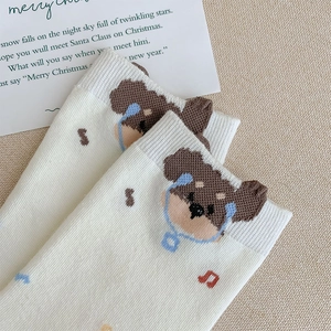Close-up of white knitted sock featuring a cute brown dog wearing blue headphones and music notes