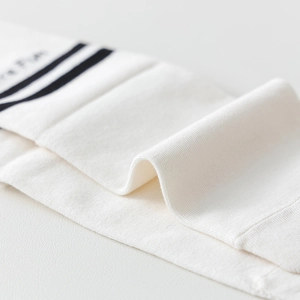 Close-up of white ribbed cotton socks with black stripes and Have Fun embroidery detail
