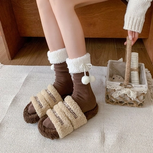 Detailed view of warm brown winter socks with white faux fur cuffs and fuzzy pom-poms