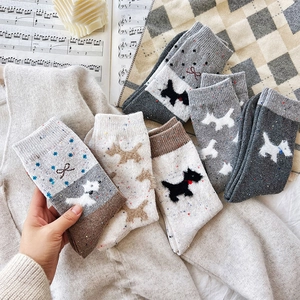 Detailed knit texture of thick wool socks with dog embroidery and bow accents
