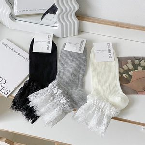 Détail de la bordure en dentelle sur des chaussettes mi-mollet en trois couleurs
