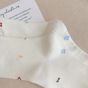 Detail of white cotton socks with colorful embroidery and a festive greeting card