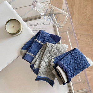 Close-up of blue and grey cable-knit socks with wavy texture and ruffled lace cuffs