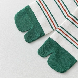 Macro detail of green and white striped split-toe socks showing fine knit texture
