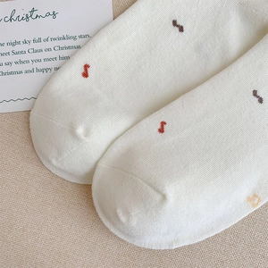 Macro detail of white knitted socks showing fine fabric texture and colorful embroidery