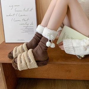 Close-up of cozy brown winter socks with white faux fur trim and cute pompom drawstrings