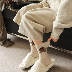 Detail of oatmeal knit socks with brown bear embroidery and soft warm texture